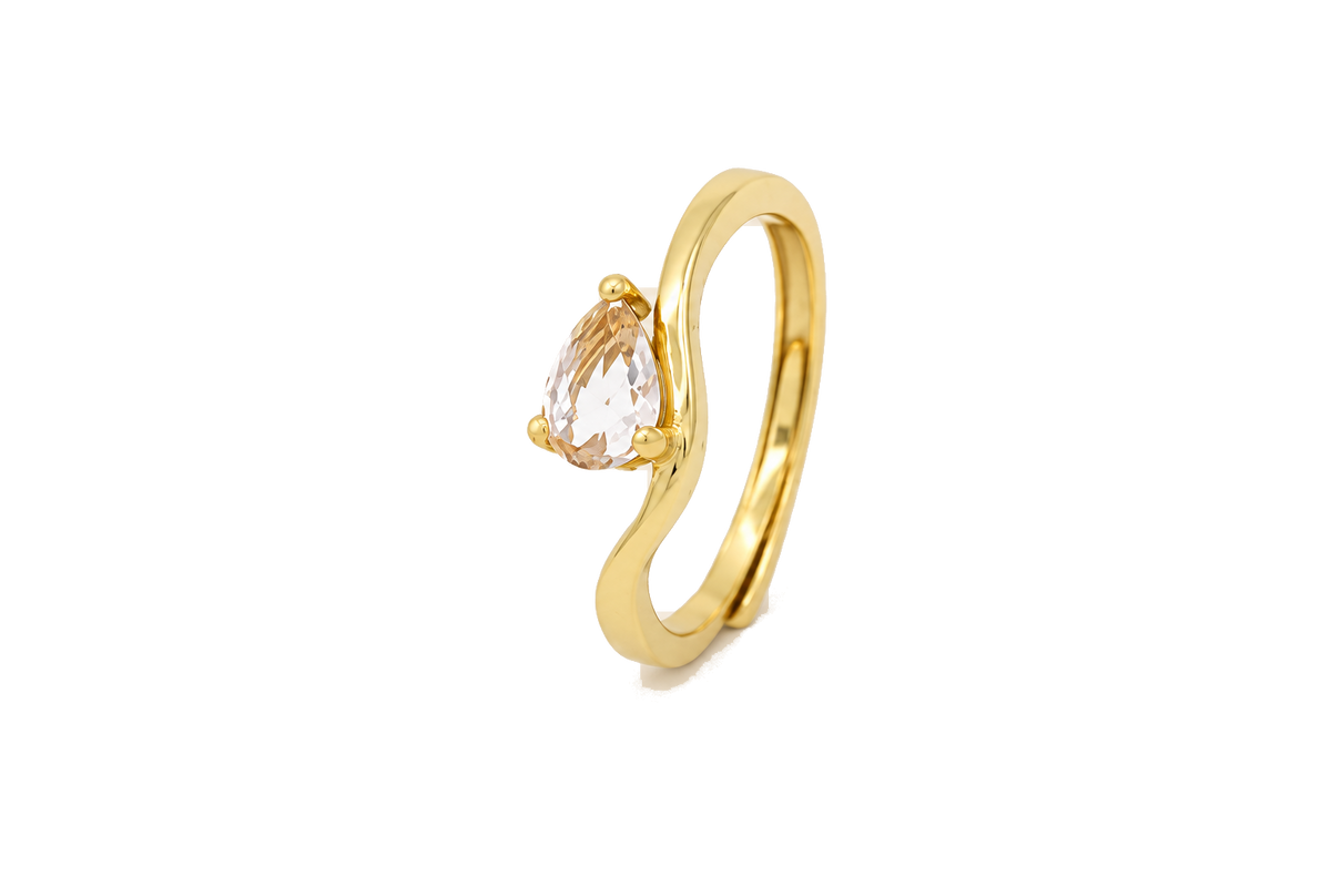 Anello con pietra a goccia, finitura dorata e pietra champagne, sfondo beige